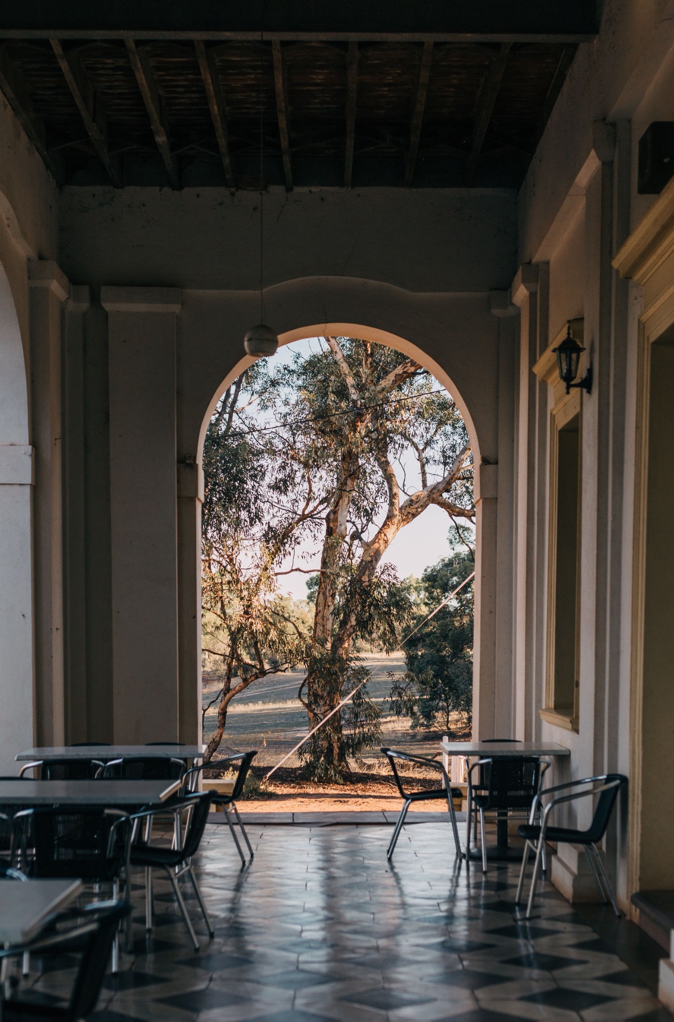 A quiet cafe terrace framed by a tall archway